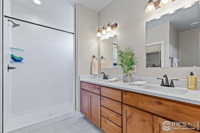 bathroom with tile flooring, tiled shower, and dual bowl vanity