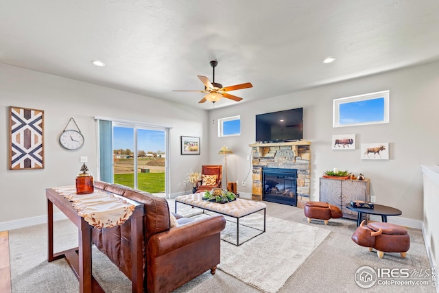 living room featuring light colored carpet, ceiling fan, and a fireplace