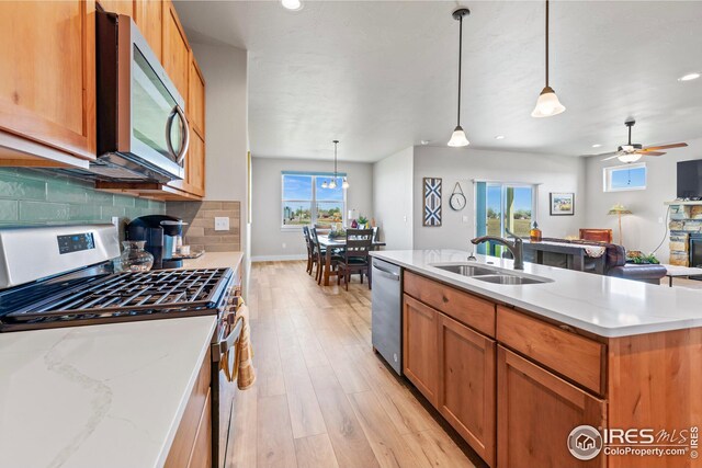 kitchen featuring appliances with stainless steel finishes, pendant lighting, ceiling fan, backsplash, and sink