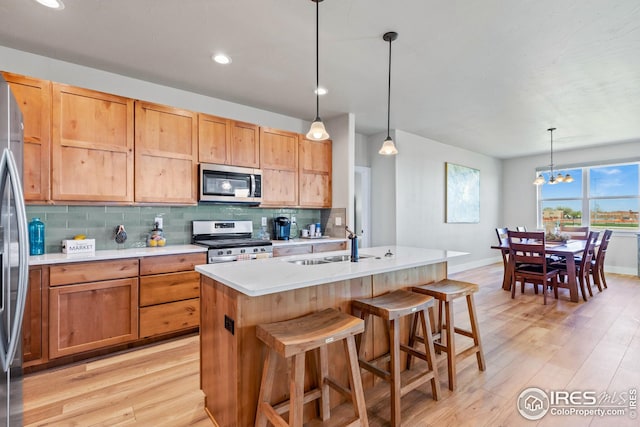 kitchen with backsplash, stainless steel appliances, a notable chandelier, decorative light fixtures, and light hardwood / wood-style flooring