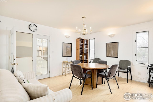 dining space with light hardwood / wood-style floors and a chandelier