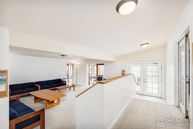 corridor with light carpet, french doors, and vaulted ceiling