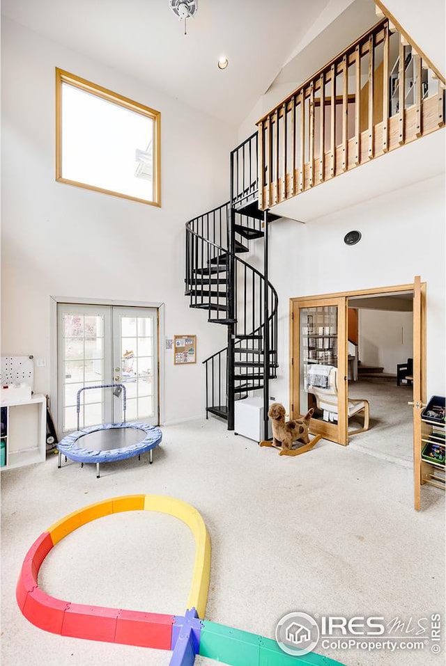 recreation room with carpet flooring, high vaulted ceiling, and french doors