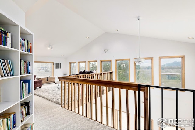 hallway with light colored carpet, high vaulted ceiling, and a chandelier