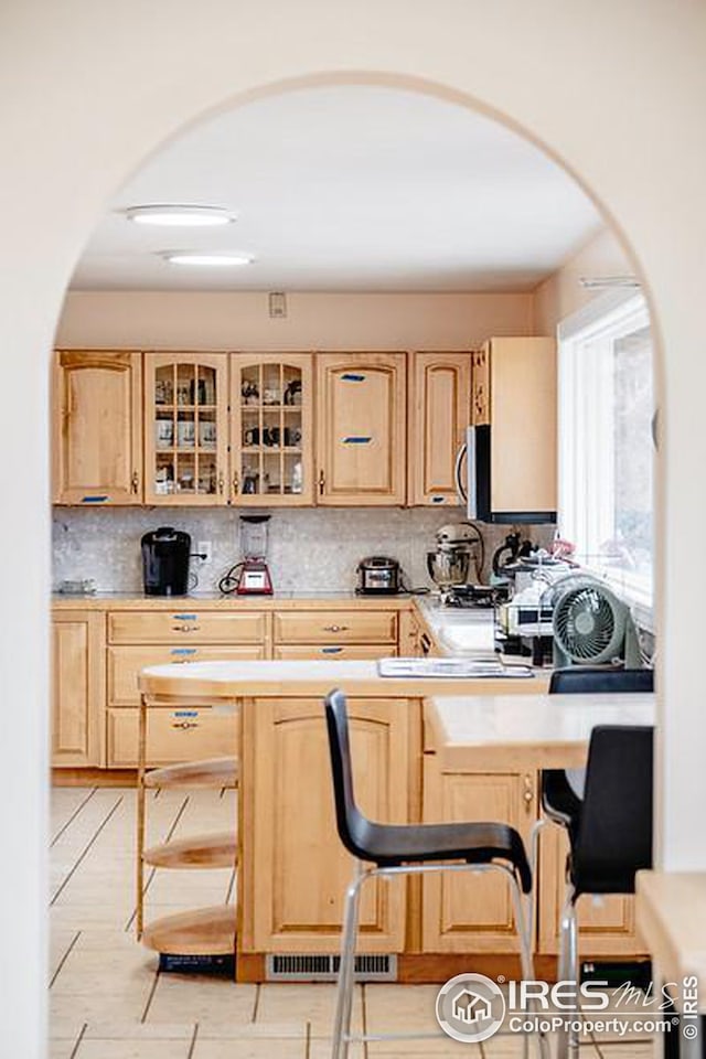 kitchen featuring light brown cabinetry and tasteful backsplash