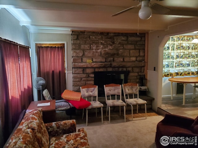 living room with a stone fireplace, ceiling fan, and ornamental molding