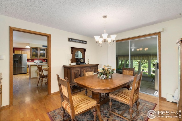 dining area featuring a textured ceiling, light hardwood / wood-style floors, an inviting chandelier, and a baseboard heating unit