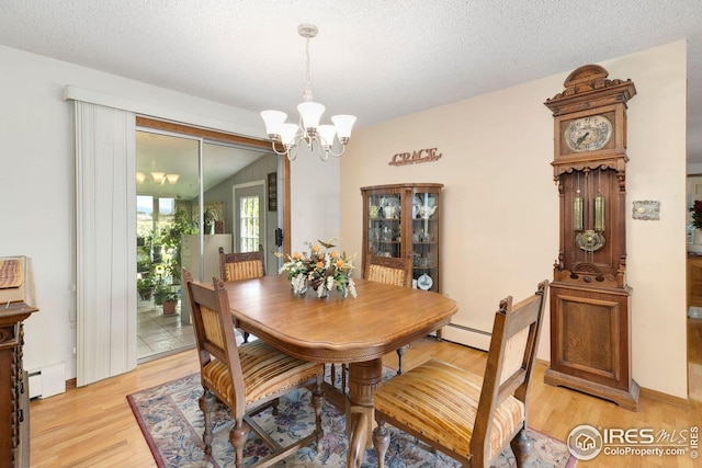 dining area with a textured ceiling, baseboard heating, a chandelier, light wood-type flooring, and vaulted ceiling