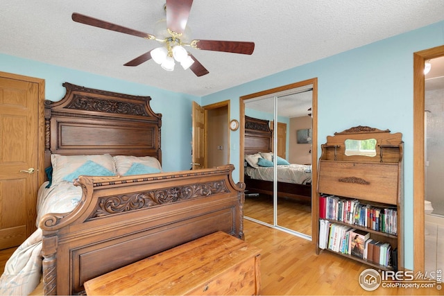 bedroom with a closet, ceiling fan, hardwood / wood-style floors, and a textured ceiling