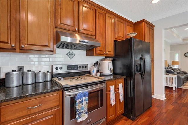 kitchen featuring tasteful backsplash, stainless steel range with electric cooktop, black fridge, brown cabinets, and under cabinet range hood