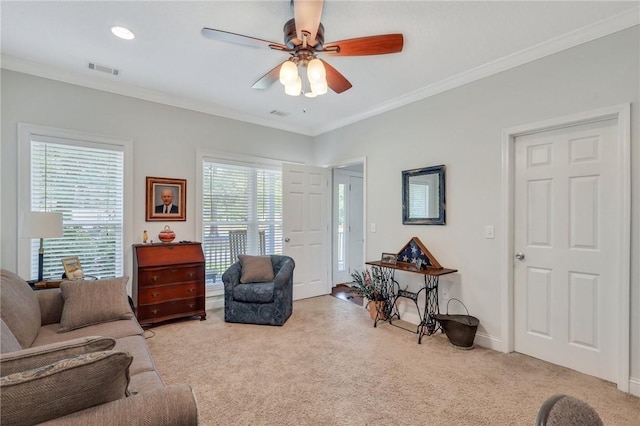 living area featuring baseboards, visible vents, light colored carpet, a ceiling fan, and ornamental molding