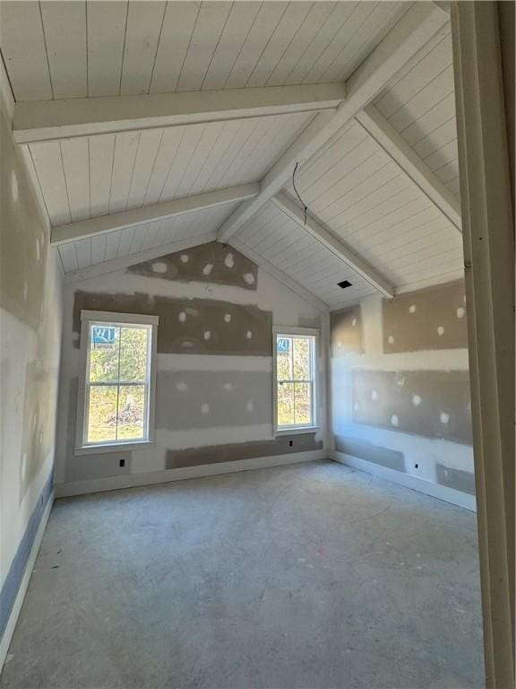 empty room with baseboards and vaulted ceiling with beams