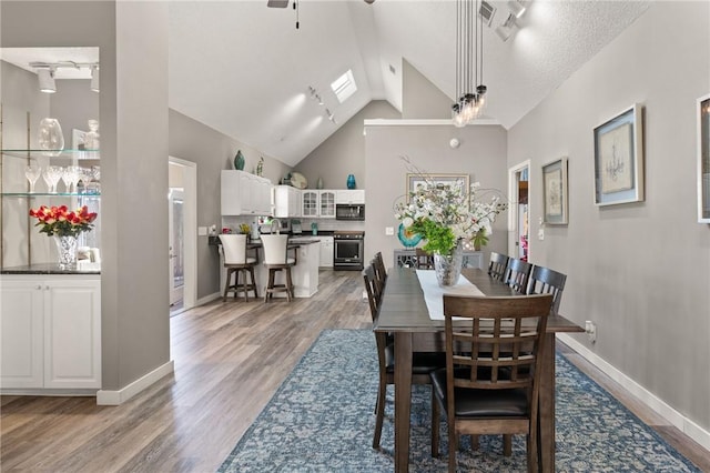 dining space featuring light wood finished floors, rail lighting, and baseboards