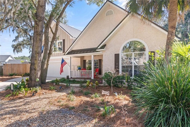 view of front of house featuring metal roof, an attached garage, fence, stucco siding, and a standing seam roof