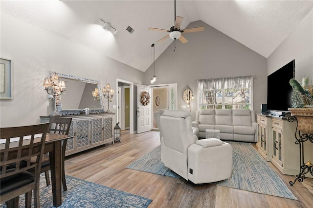 living room featuring high vaulted ceiling, wood finished floors, visible vents, and a ceiling fan