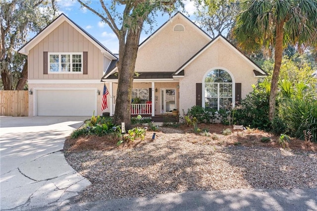 view of front of property featuring covered porch, concrete driveway, fence, and a garage