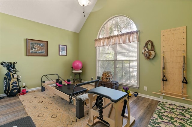 exercise room with high vaulted ceiling, baseboards, and wood finished floors