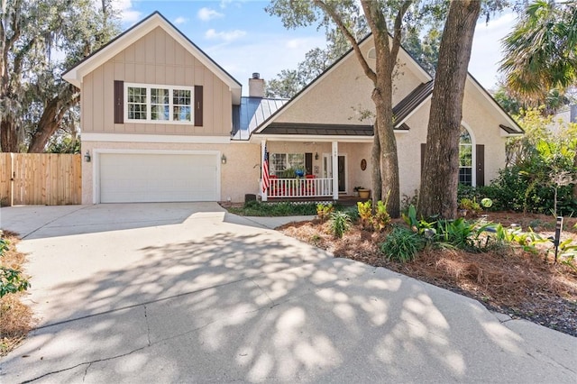 view of front of home featuring a garage, driveway, metal roof, a standing seam roof, and a porch