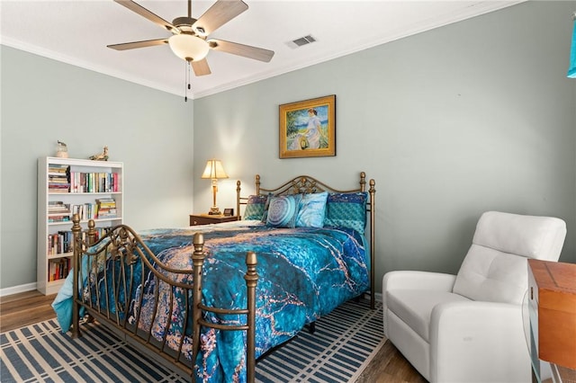 bedroom with baseboards, visible vents, a ceiling fan, wood finished floors, and crown molding