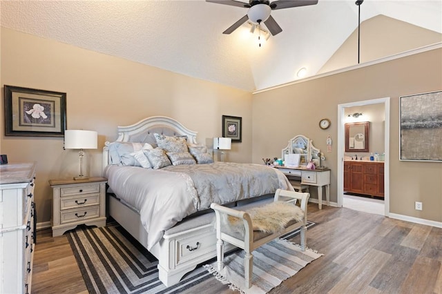 bedroom featuring ensuite bathroom, a sink, wood finished floors, baseboards, and vaulted ceiling