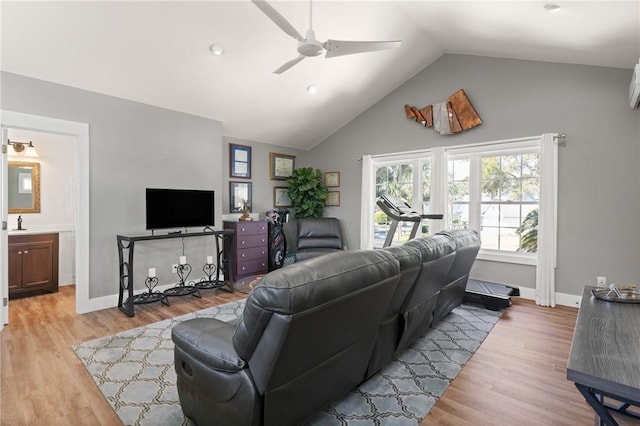 living area featuring light wood-style floors, vaulted ceiling, baseboards, and a ceiling fan