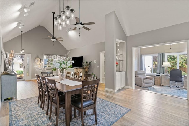 dining room with high vaulted ceiling, baseboards, and light wood finished floors