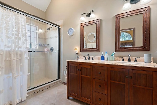 bathroom featuring double vanity, a shower stall, a sink, and tile patterned floors