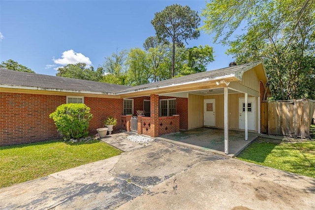 135 Kensington Dr, Brunswick, GA 31525 - ranch-style home with concrete driveway, a front lawn, a carport, fence, and brick siding