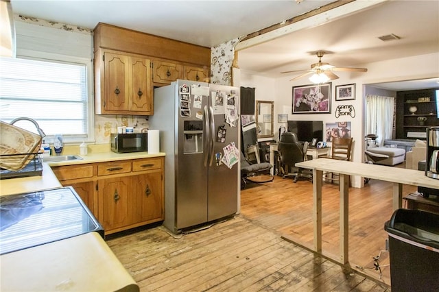 300 Community Dr, Waycross, GA 31501 - kitchen with stainless steel fridge with ice dispenser, black microwave, light countertops, light wood-type flooring, and ceiling fan