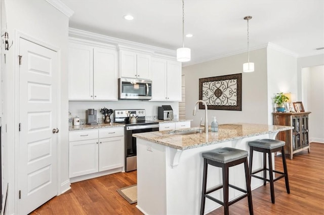 139 Allie Loop, Brunswick, GA 31525 - kitchen featuring appliances with stainless steel finishes, crown molding, wood finished floors, a kitchen breakfast bar, and white cabinetry