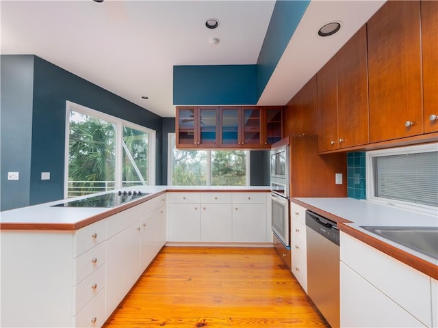 kitchen with appliances with stainless steel finishes, backsplash, light hardwood / wood-style flooring, and white cabinetry