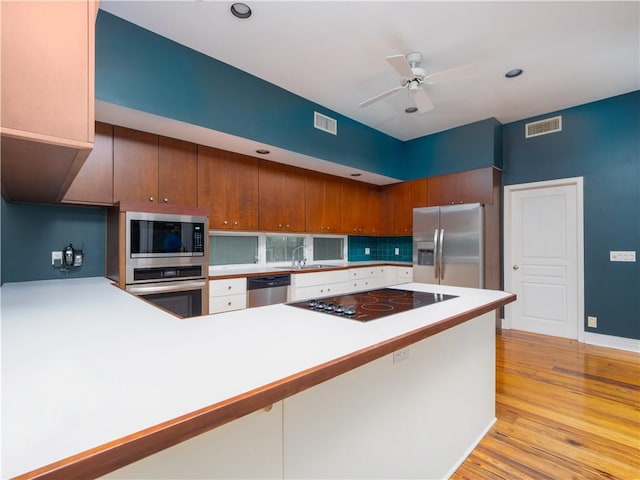 kitchen featuring sink, kitchen peninsula, stainless steel appliances, and light hardwood / wood-style flooring