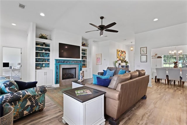 1317 Kyles Loop NE, Townsend, GA 31331 - living room featuring a ceiling fan, light wood-style flooring, a fireplace, built in shelves, and a chandelier