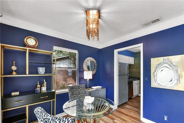 dining space featuring visible vents, a textured ceiling, baseboards, and wood finished floors