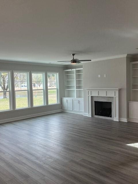 unfurnished living room featuring ceiling fan, built in features, wood-type flooring, and ornamental molding