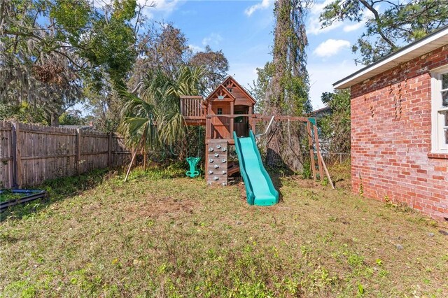 view of playground featuring a fenced backyard and a lawn