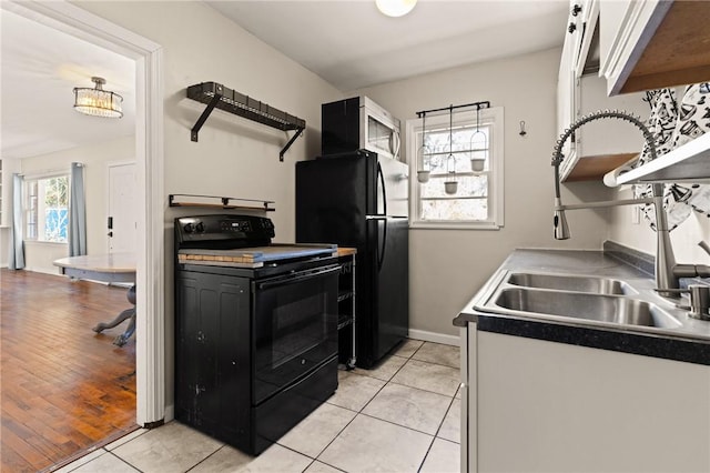 kitchen featuring light tile patterned floors, white cabinets, black appliances, open shelves, and a sink