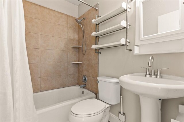 bathroom with a sink, shower / bath combo with shower curtain, and toilet