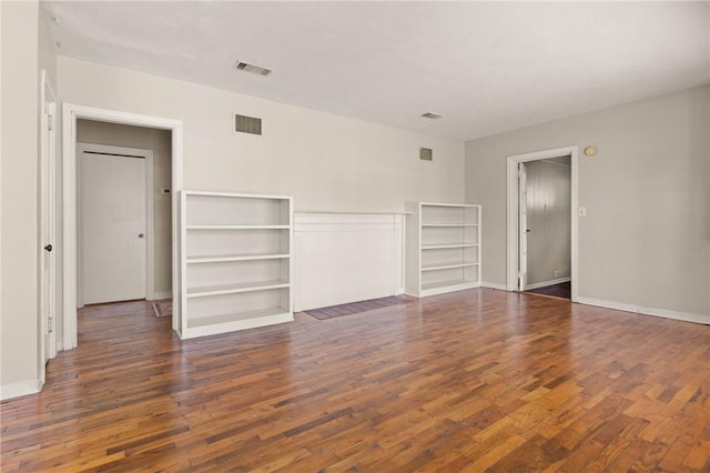 unfurnished room featuring wood-type flooring, visible vents, and baseboards