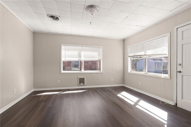 spare room featuring dark wood-type flooring, visible vents, and baseboards