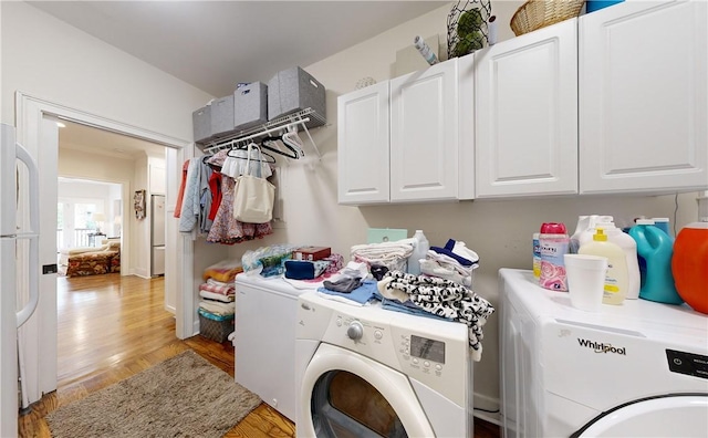 laundry room featuring light hardwood / wood-style flooring, washer and clothes dryer, and cabinets