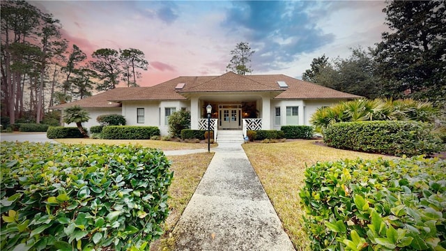 view of front of home with french doors and a lawn