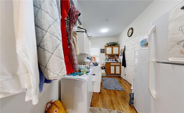 clothes washing area with washer and clothes dryer and light wood-type flooring