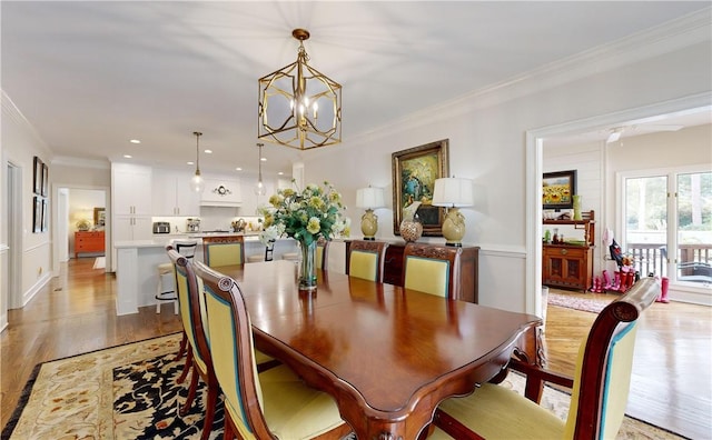 dining area featuring ornamental molding, light hardwood / wood-style flooring, and a notable chandelier