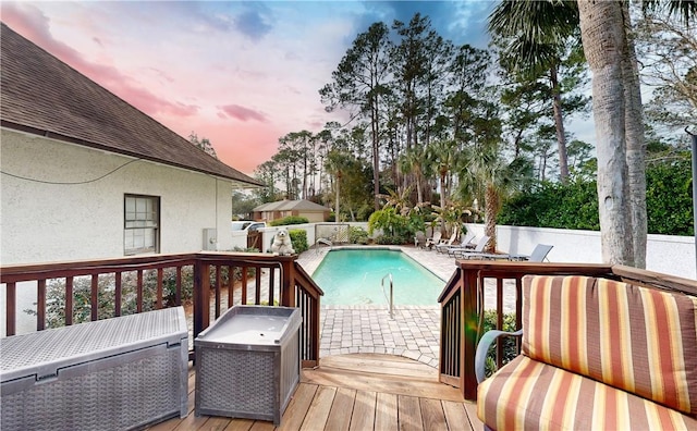 pool at dusk featuring a wooden deck and a patio