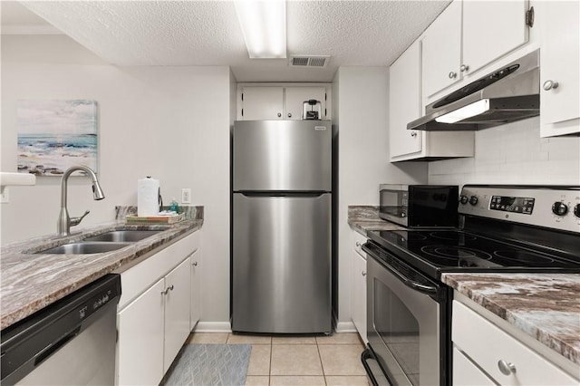 kitchen with appliances with stainless steel finishes, a textured ceiling, sink, light tile patterned floors, and white cabinets