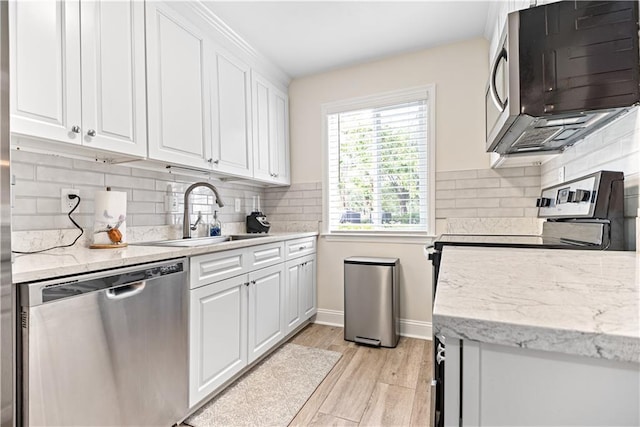 850 Mallery St Unit 3M, Saint Simons Island, GA 31522 - kitchen featuring stainless steel appliances, white cabinets, light wood-style floors, and backsplash