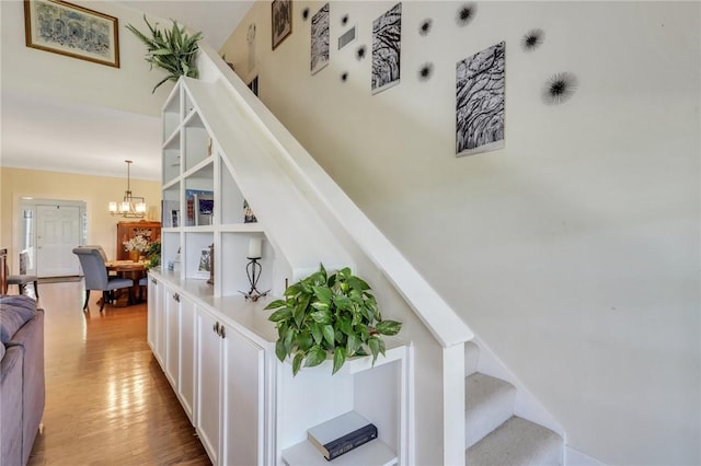 stairway featuring a notable chandelier and wood finished floors