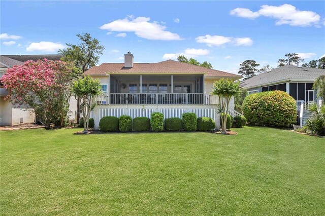 rear view of property featuring a yard, a chimney, and a sunroom