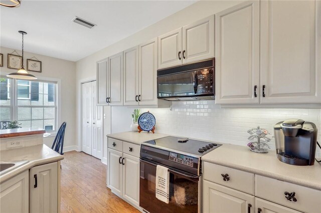 kitchen with visible vents, light countertops, backsplash, black appliances, and pendant lighting